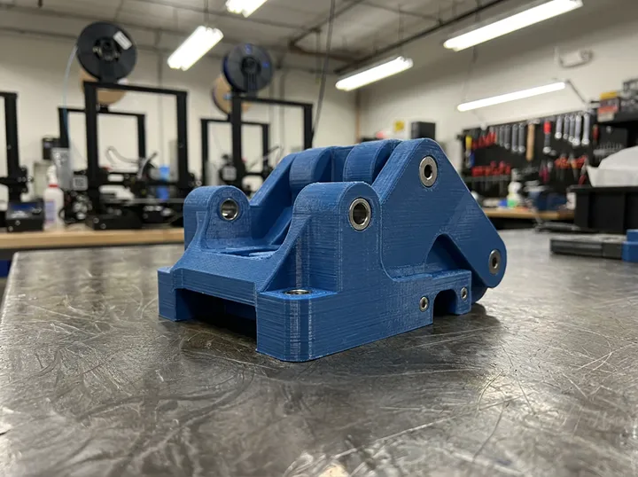 3D baskı atölyesinde üretim sonrası masada duran, katmanlı yapısı belirgin FDM baskı jig aparatı.