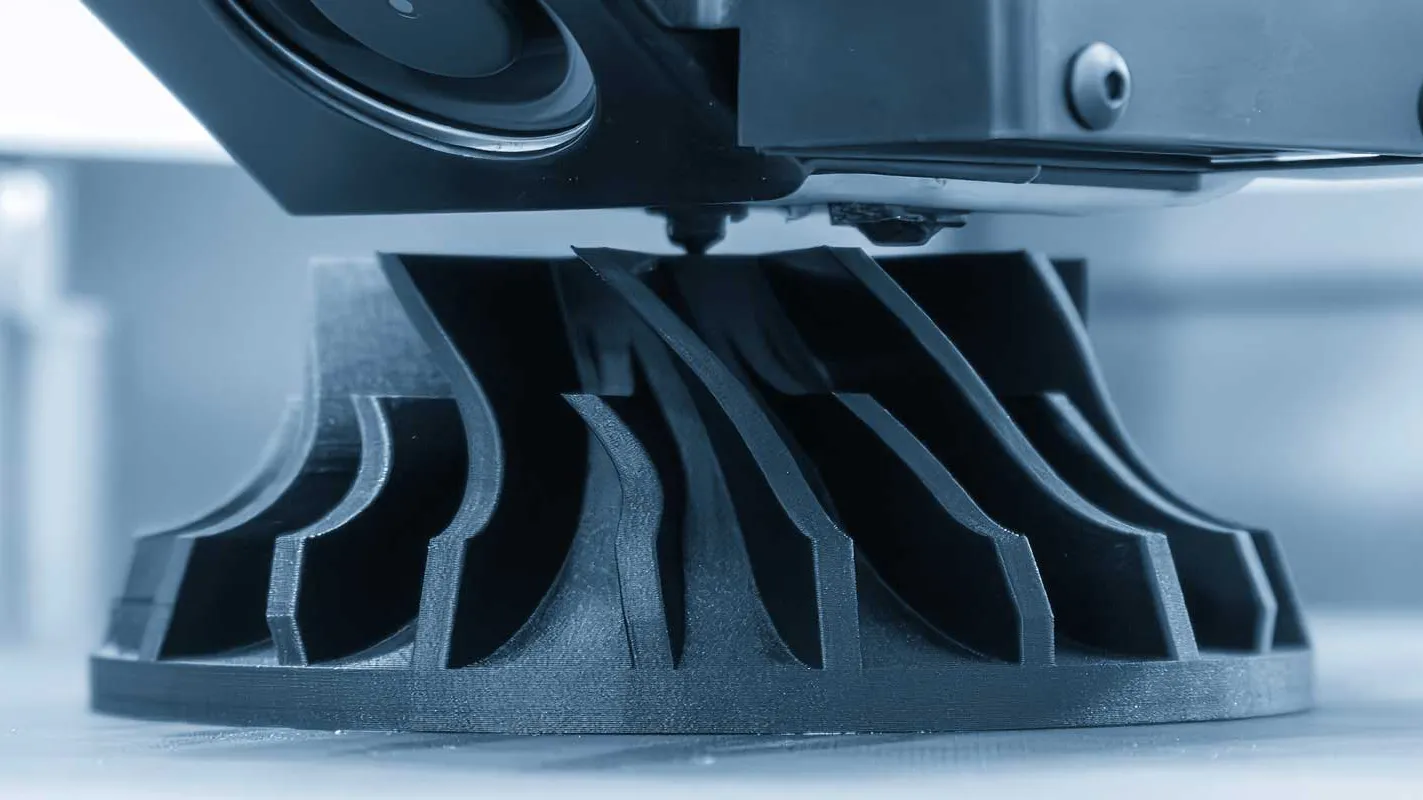 FDM baskı nedir sorusunu görselleştiren, 3D yazıcı nozülünün (uç) siyah filamenti eriterek katman katman endüstriyel bir türbin parçasını oluşturduğu üretim anı.